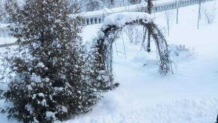 4 to the video, A snow-covered arch in the background, it's snowing in a winter park - Powered by Adobe