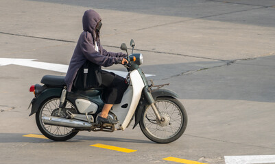 Fototapeta na wymiar A woman with a hood rides a motorcycle
