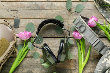 Military equipment with tulips and eucalyptus on wooden background. Hello spring
