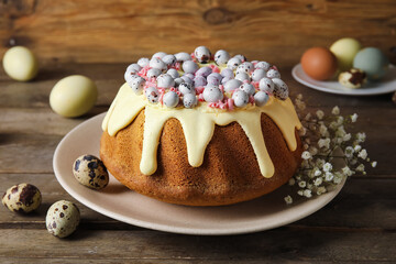 Plate with delicious Easter cake, gypsophila flowers and eggs on wooden table