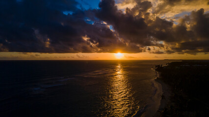 Obraz premium aerial drone image of beautiful beach during sunset in Punta Cana. the golden sunset feels the sky with crimson orange and crystal clear water 