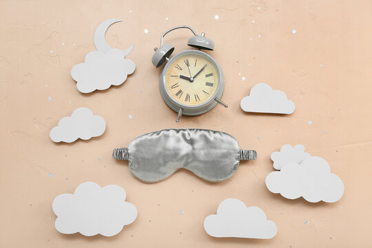 Composition with alarm clock, sleeping mask and paper decor on color background. World Sleep Day concept