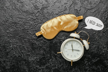 Alarm clock, sleeping mask and speech bubble with text I NEED SLEEP on dark background. World Sleep Day concept