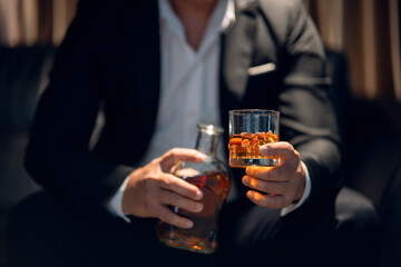 Businessman sitting and holding glass of whiskey