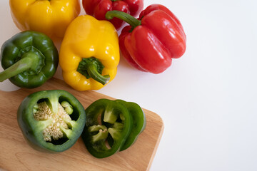 Top view of cutting sweet bell pepper on the wooden board isolated on white background.