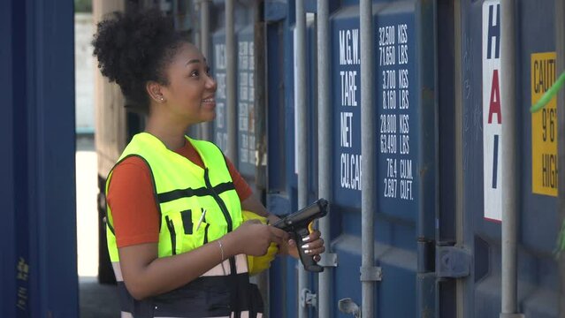 african american inspector woman checking list inventory by scanning barcode loading Containers box at warehouse logistic in Cargo.