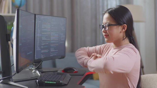 Asian Teen Girl Programmer Stretching While Creating Software Engineer Developing App, Program, Video Game On Desktop Computer At Home. Terminal With Coding Language 
