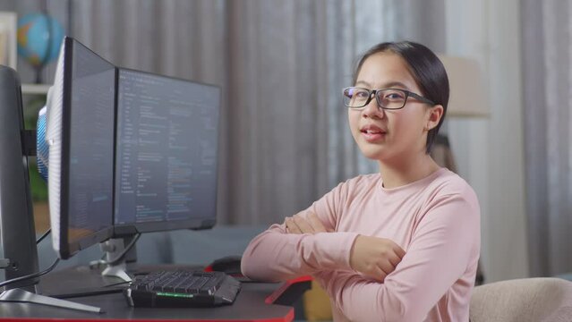 Asian Teen Girl Programmer Smiling And Crossing Her Arms While Creating Software Engineer Developing App, Program, Video Game On Desktop Computer At Home
