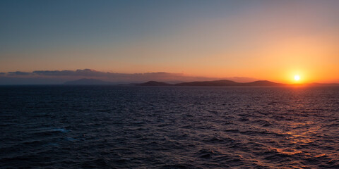 Rocky Island on Mediterranean Sea. Rinia near Mikonos, Greece, Europe. Nature Background Panorama. Sunrise Sky