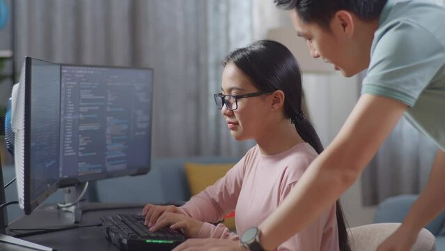 Asian Father Teaching His Daughter Creating Software Engineer Developing App, Program, Video Game On Desktop Computer At Home. Terminal With Coding Language
