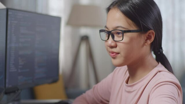 Close Up Of Asian Teen Girl Programmer Smiling And Crossing Her Arms While Creating Software Engineer Developing App, Program, Video Game On Desktop Computer At Home
