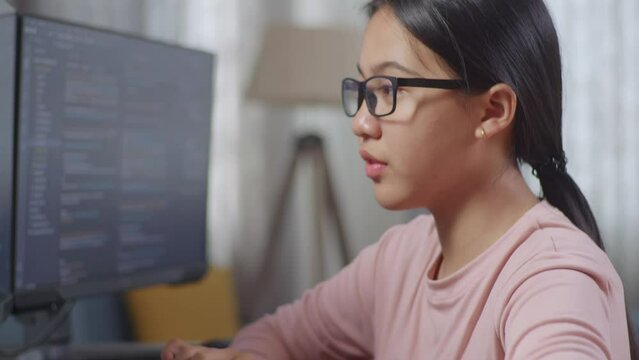 Close Up Of Asian Teen Girl Programmer Yawning While Creating Innovative Software Engineer Developing App, Program, Video Game On Desktop Computer At Home. Terminal With Coding Language 

