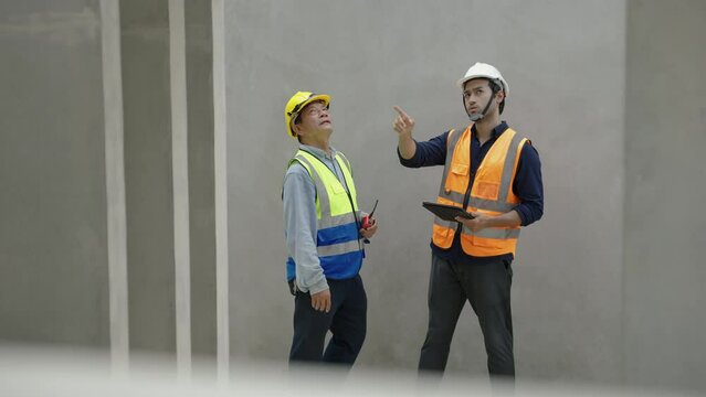 Engineers are inspecting work inside a precast concrete factory producing house walls, columns or beams.

