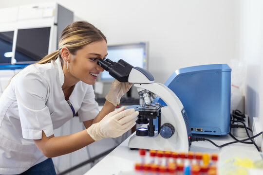 Scientist biochemist or microbiologist working research with a microscope in laboratory.