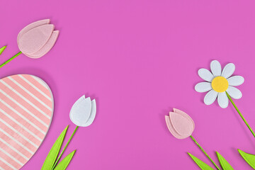 Felt tulip and daisy spring flowers and wooden Easter egg on purple background