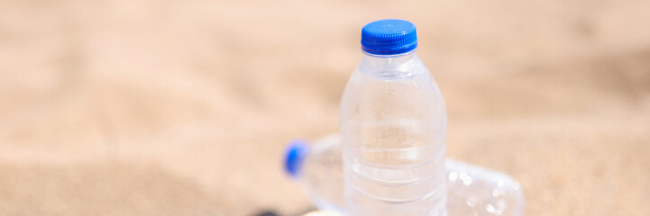Cold drinking water in transparent bottles on sandy beach sea