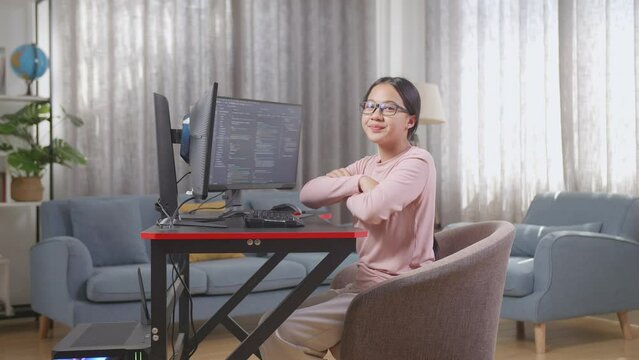 Asian Teen Girl Programmer Smiling And Crossing Her Arms While Creating Software Engineer Developing App, Program, Video Game On Desktop Computer At Home
