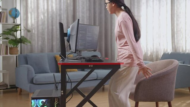 Asian Teen Girl Programmer Walking Into The Working Space Before Sitting To Creating Software Engineer Developing App, Program, Video Game On Desktop Computer At Home
