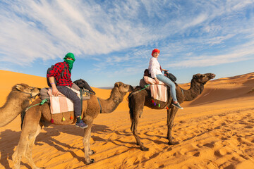 Young couple riding a camel in the middle of a desert in marocco.