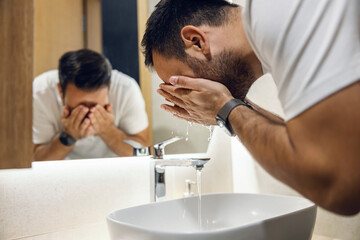 A man washing his face in the morning.