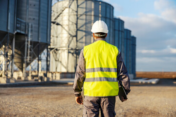 An industry worker walking towards silos with tablet in his hands. © Dusan Petkovic