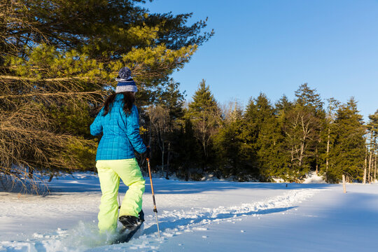 A teenage girl snowshoes across a frozen beaver pond in Epping, New Hampshire.