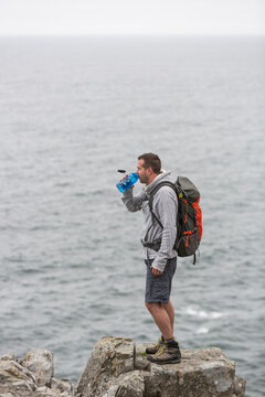 Hiker standing on rock by sea in Acadia National Park, Maine, USA