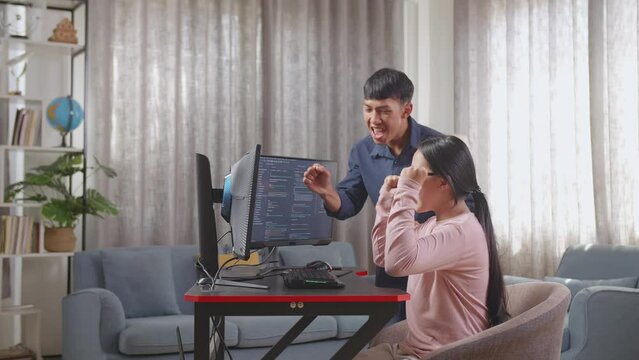 Happy Asian Teen Girl And Boy Celebrating Succeed Creating Software Engineer Developing App, Program, Video Game On Desktop Computer At Home. Terminal With Coding Language

