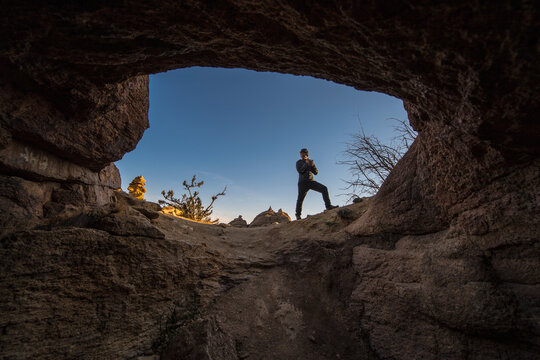 Man standing at entrance of cave, Baga Gazariin Chuluu, Gobi Desert, Mongolia