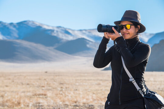 Woman photographing barren landscape, Olgiy, Bayan-Olgiy, Mongolia