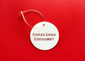 On red background, price tag with text written CONSCIOUS CONSUMER, shopper who looks beyond the label, make buying decisions on local, ethical and environmentally friendly products