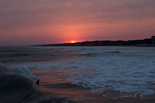 A surfer catches a wave as the sun sets.