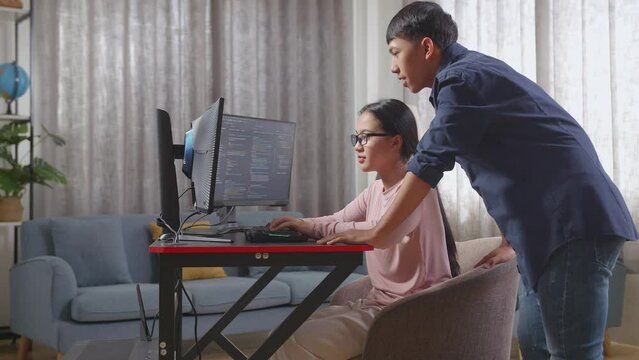 Asian Boy Teaching His Sister Creating Software Engineer Developing App, Program, Video Game On Desktop Computer At Home. Terminal With Coding Language
