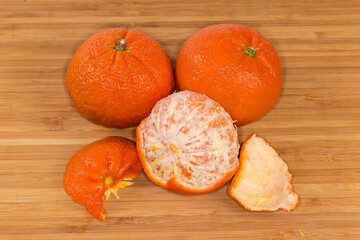 Whole and partly peeled tangerines Murcott on a wooden surface