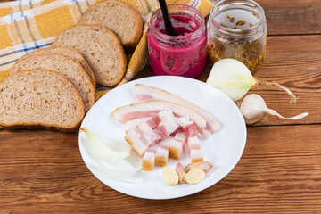 Salted pork fatback slices, bread and seasonings on rustic table