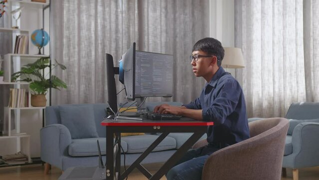 Asian Boy Programmer Creating Innovative Software Engineer Developing App, Program, Video Game On Desktop Computer At Home. Terminal With Coding Language 
