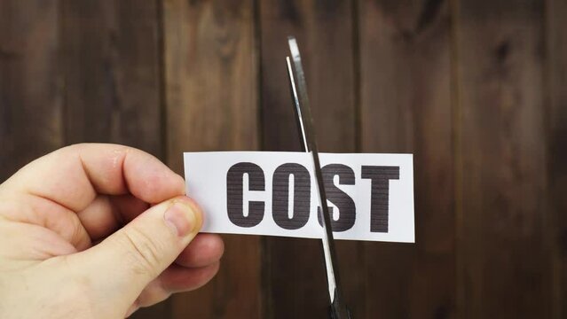 A man cuts with scissors a strip of paper with the inscription - COST.
