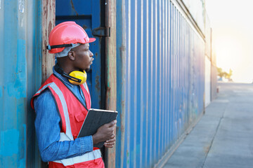 Foreman using tablet and walkie talkie radio control loading containers box. Engineer or worker with safety hat work at container cargo site and checking industrial container cargo freight ship.