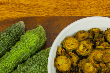 Fresh green organic Bitter gaud vegetable kept along with cooked bitter gaud on a wooden table with...