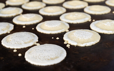 Obraz na płótnie Canvas Small pancakes are baked on a hot plate. Street market