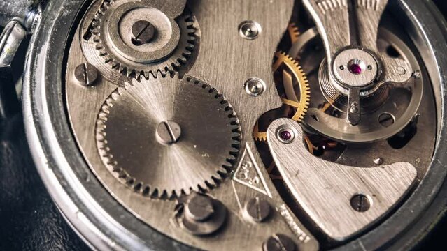 Timelapse of vintage stopwatch mechanism close-up. Round clock watch mechanism working in a macro. Old retro clockwork gears, cogwheels, and pendulum movement inside the rotation ancient stopwatch.