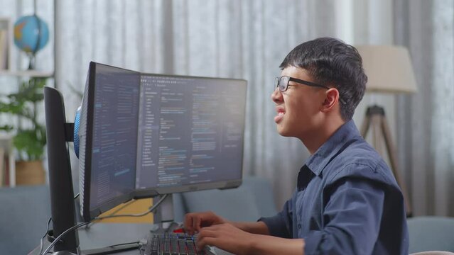 Asian Boy Programmer Having A Backache While Creating Software Engineer Developing App, Program, Video Game On Desktop Computer At Home. Terminal With Coding Language 
