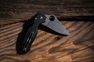 Folding pocket knife on a wooden background. Vintage photo of a knife. Knife in folded position....