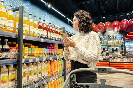 a woman choose juice from a grocery list on her phone in a supermarket
