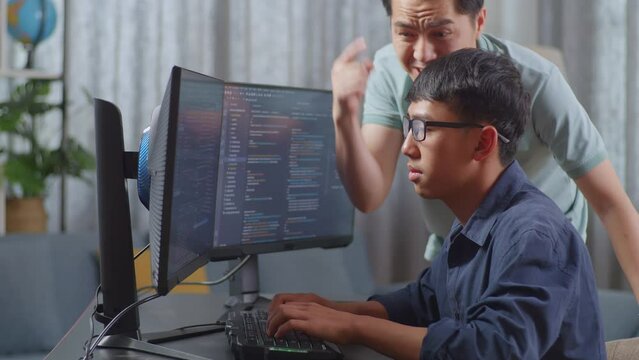 Asian Father Shouting At His Son While Creating Software Engineer Developing App, Program, Video Game On Desktop Computer At Home. Terminal With Coding Language
