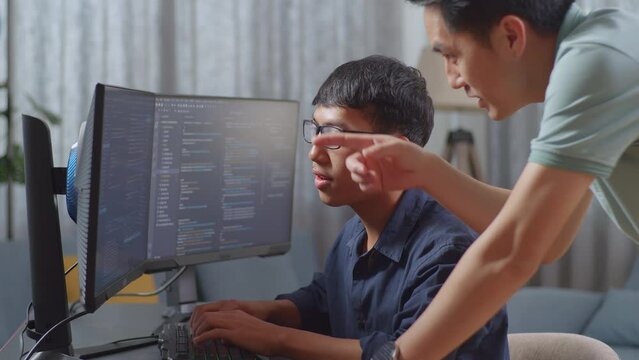 Asian Father Teaching His Son Creating Software Engineer Developing App, Program, Video Game On Desktop Computer At Home. Terminal With Coding Language
