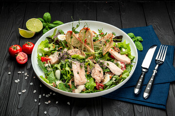 Fresh caesar salad in white plate on dark wooden table.