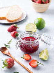 Homemade strawberry jam. Preserved food in a glass jar with fresh organic berries on a light background with fresh bread. Concept of sweet breakfast.
