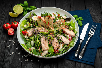 Fresh caesar salad in white plate on dark wooden table.