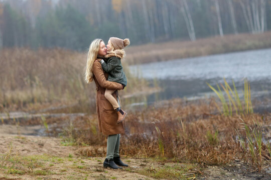 a beautiful blonde girl and a daughter of 6 years old are walking in the autumn park